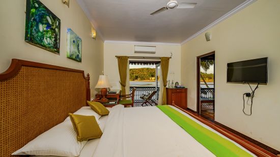 A double bed tv ac fan and balcony inside Coral - River View room at neemrana s three waters