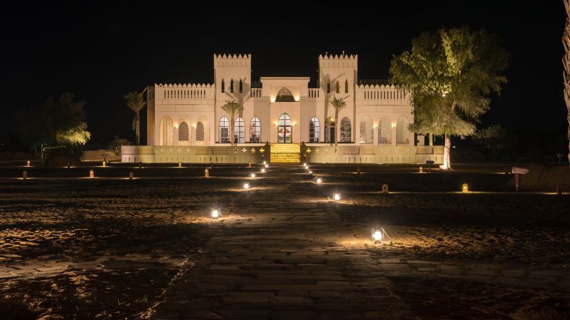 A beautiful view of the hotel facade at night surrounded by palm trees - Karwaan Jaisalmer