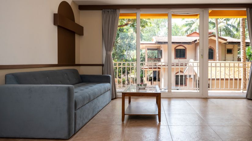 The living area with a sofa and a coffee table with floor to ceiling windows in the background - Richmonde Ananta Elite, Goa