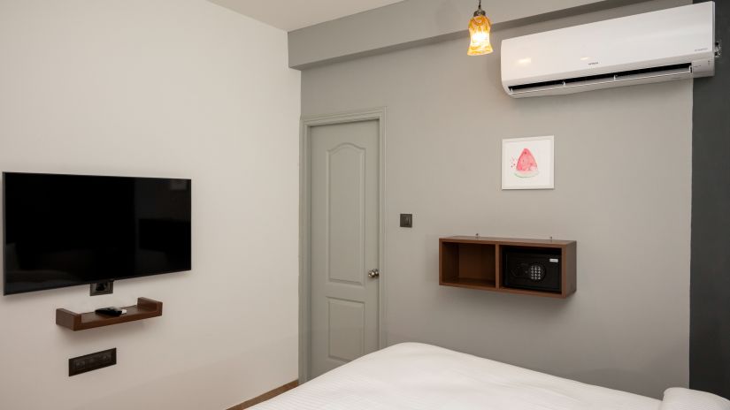 The bedroom with an LED TV, an AC and grey walls