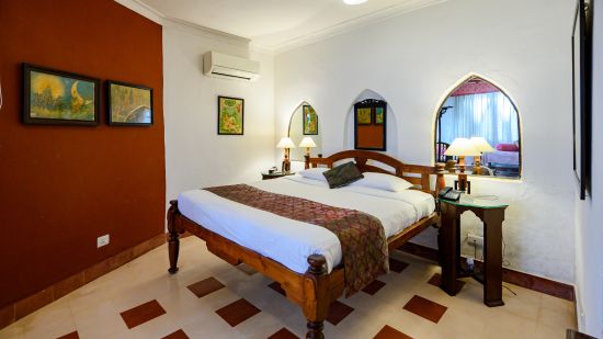 Hill Fort Kesroli 14th Century Alwar - interior view of the Naruka Burj - Countryside View room with a queen size bed, burgundy-coloured wall and lamps on either side 