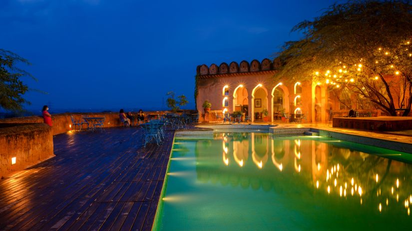 A vibrant blue pool with the resort at the background - Hill Fort Kesroli Alwar Rajasthan