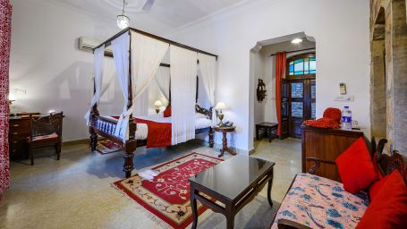 Deo Bagh - 17th Century, Gwalior - a king size bed covered with sheets kept beside a sofa set at the Jayaji Vilas room in Gwalior