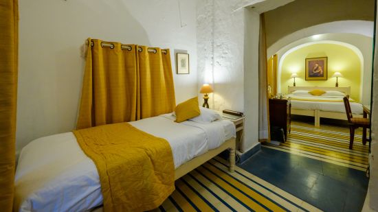 Hill Fort Kesroli 14th Century Alwar - interior view of the Swagat Mahal room wit a single bed and yellow decor