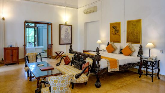 An overview of the Maharaja Sahib Singh room with sofas, coffee table in front of the tv with king size bed in the background - The Baradari palace