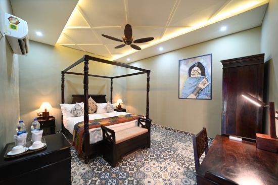 alt-text The bedroom of the Luxury Cottage is adorned with a beautiful painting and equipped with several amenities - Karwaan Jaisalmer