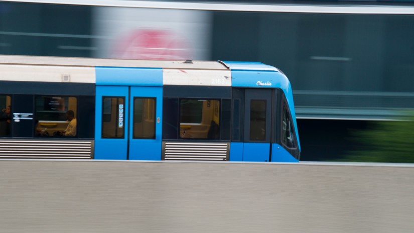 A blue and silver metro train going fast on a track