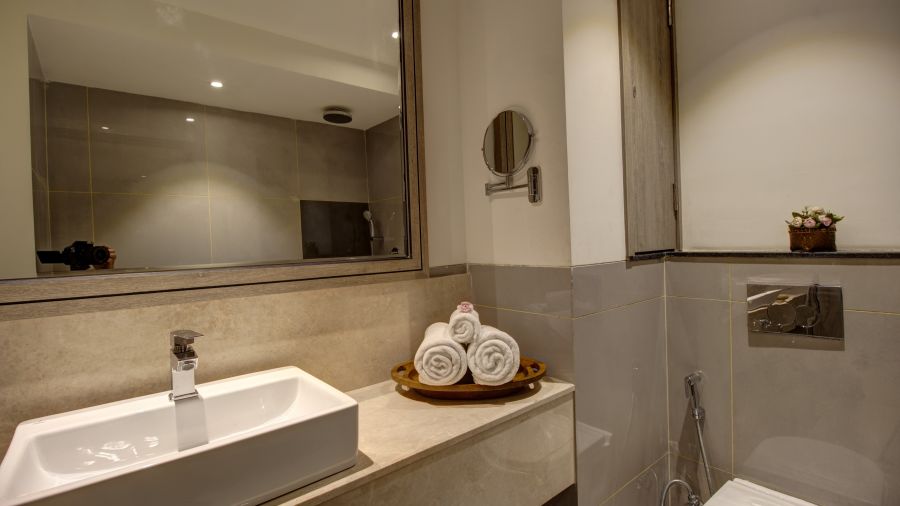 Overview of the bathroom with the sink and wash towels kept on the counter inside Premium Suite - Rhythm Gurugram