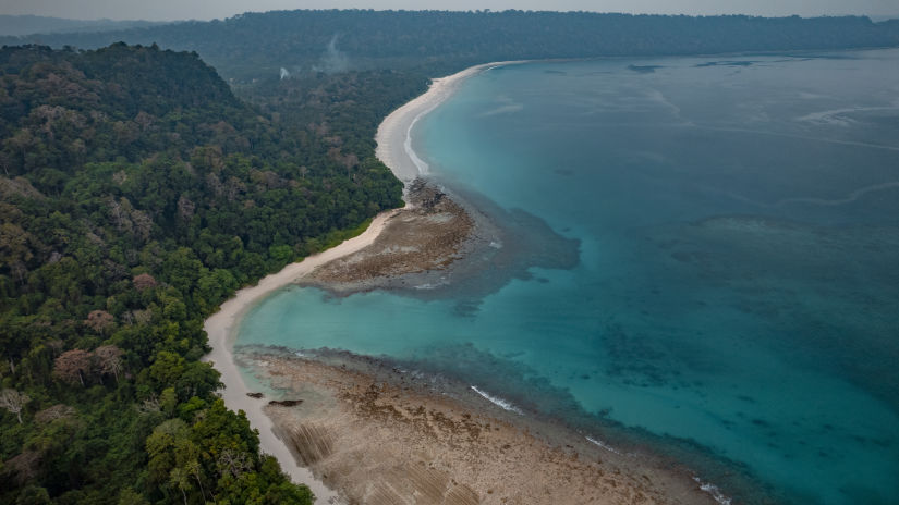 A coastal stretch enveloped by towering mountains.