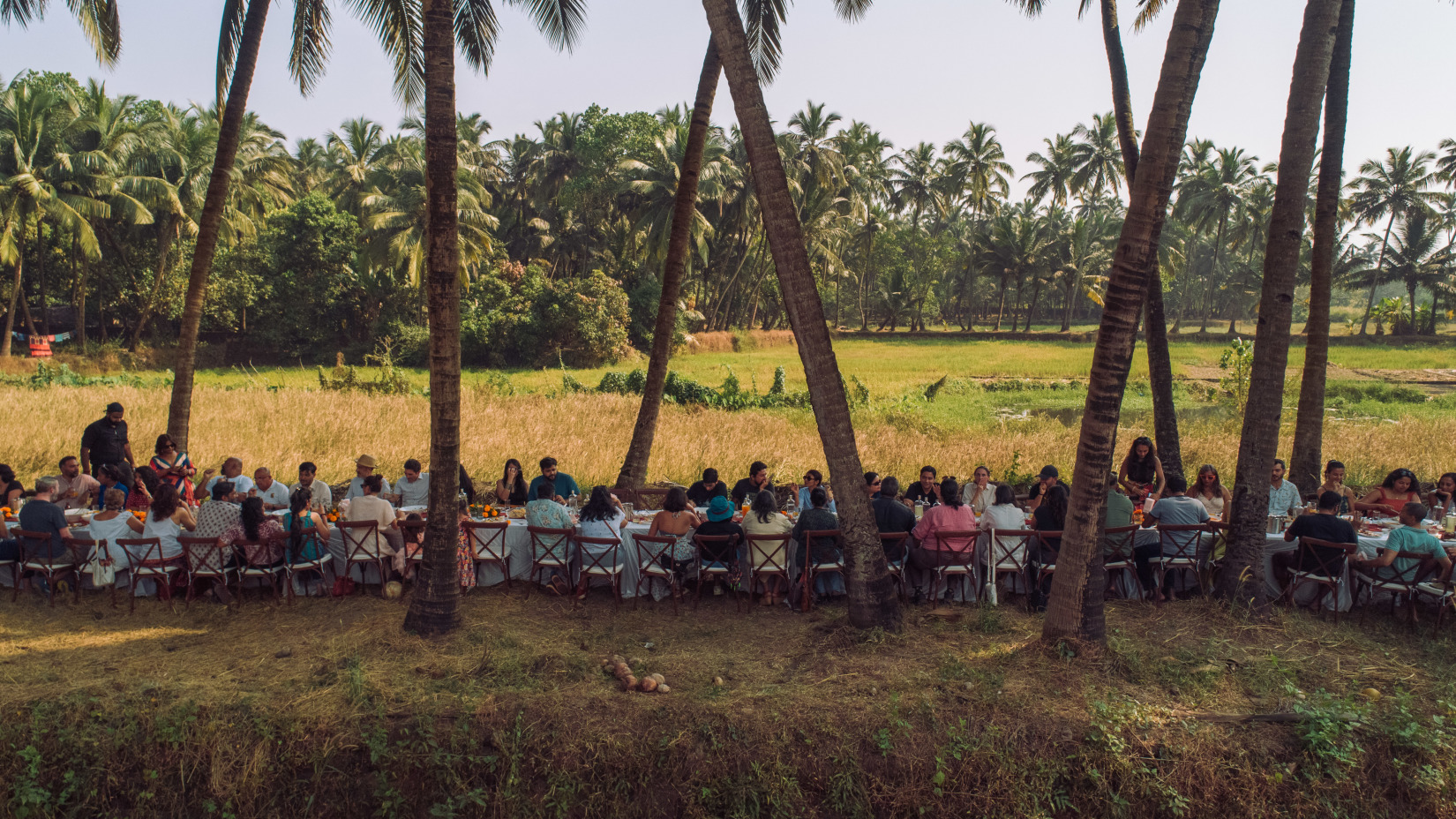 A group of people having a feast in a field - Villa in Palms by V Escapes