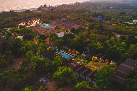 alt-text Aerial view of our resort in Mandrem featuring a night panorama with the swimming pool, the surroundings and the cottages 62