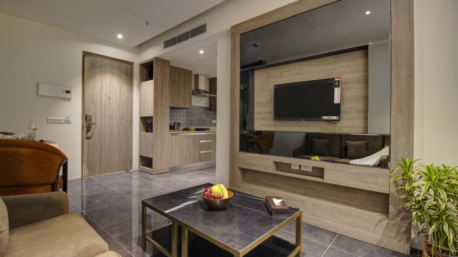 living area inside the Premium Suite with a tv wall mounted, sofas and a coffee table - Rhythm Gurugram