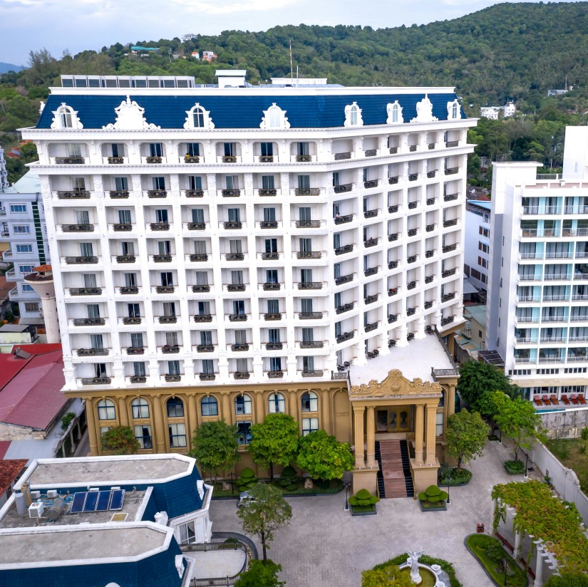 A grand, white colonial-style hotel building with balconies and a large entrance