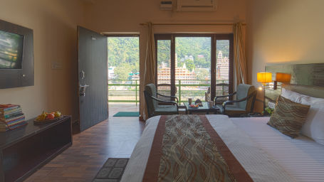 Side view of Deluxe room with large bed, basic amenities and a windows- Kunwar Residency