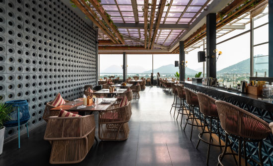 alt-text Side view ,A series of elegantly decorated seating areas inside Taro, offering a stunning view of Udaipur's magnificent scenery at Parallel hotel udaipur 