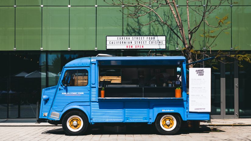 A blue food truck parked on the side of the road 