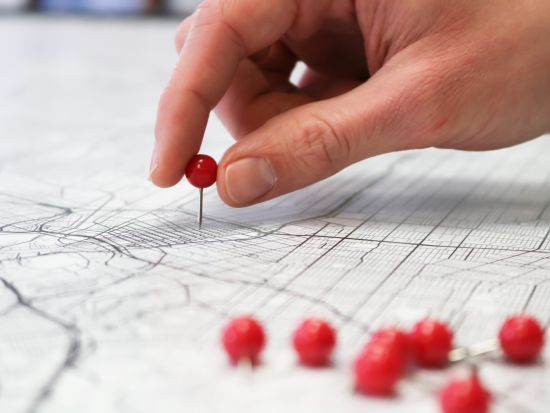 a person pinning a red dot on a map with other pins on the side