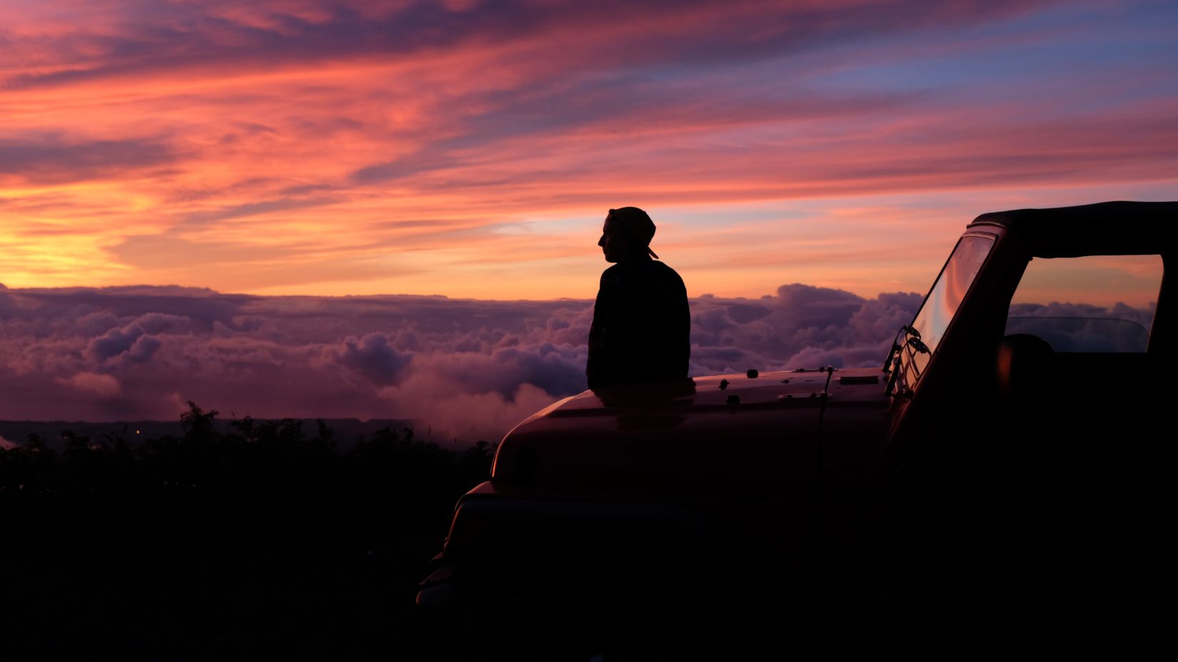 person sitting on the hood of a car