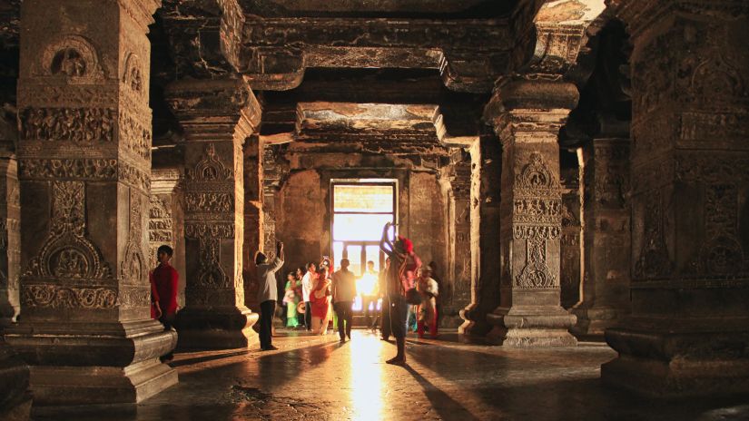 an image taken from inside a Temple with the entrance in the background and people walking from it