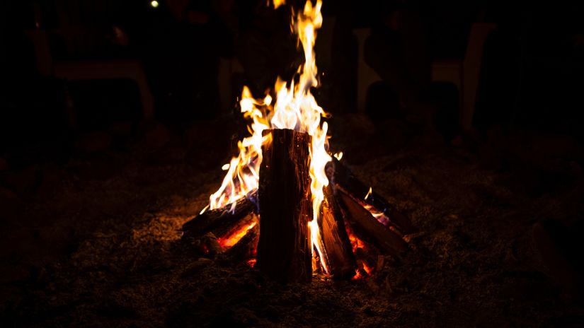 A bonfire burning with logs stacked up against each other in a small space