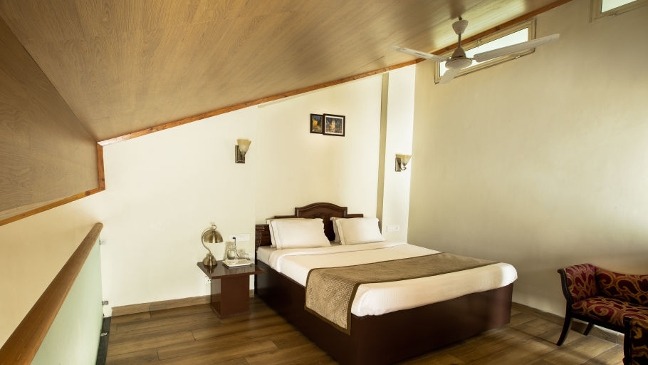 A cosy room with a queen size bed with wooden ceiling and pristine white bedsheets along with room amenities - Lamrin Norwood Green, Palampur