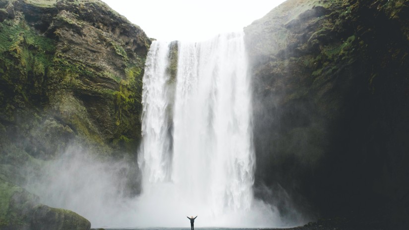 a beautiful waterfall captured during the day in between the mountain