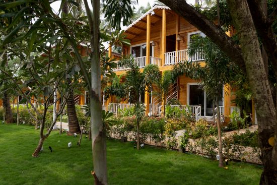 alt-text cottage facade with grass area in the foreground that has trees on it - Aralea Beach Resort by Stone Wood, Morjim