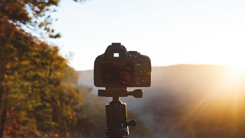 an image of a camera on a tripod with the sun shining in the background