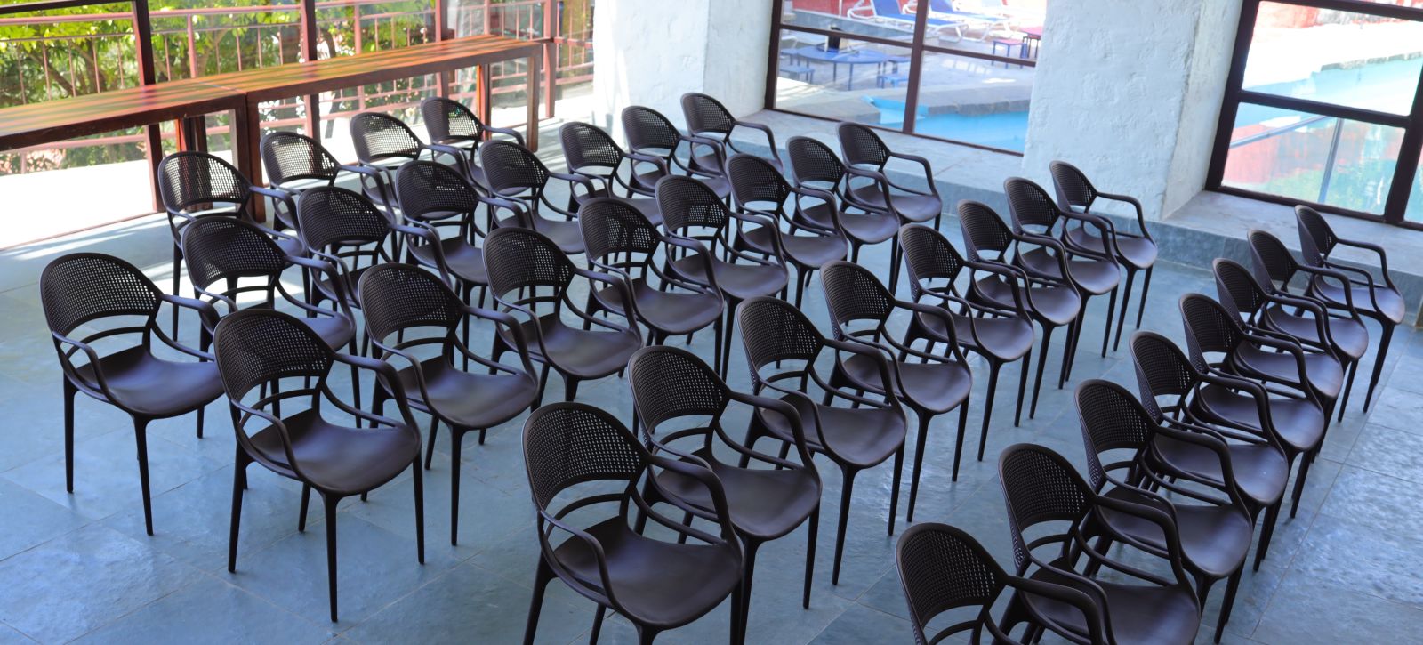 Banquet hall with rows of plastic chairs and a view of the pool.