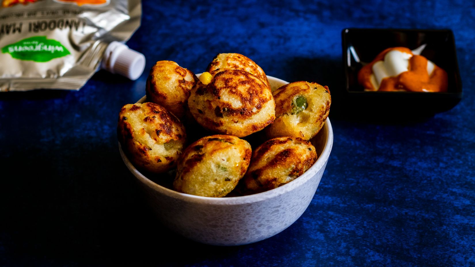 a close up shot of daal baati churma in a bowl with blue velvet cloth on the table