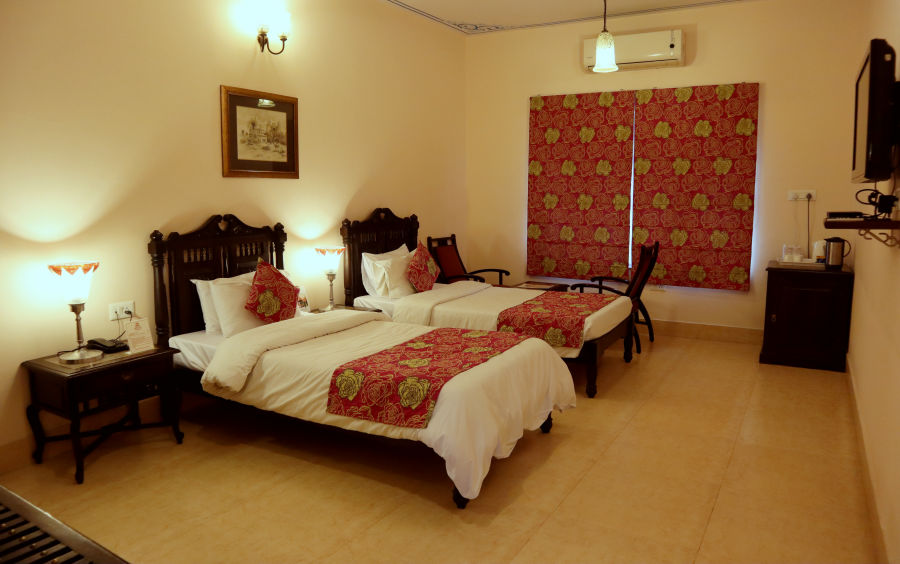 alt-text Twin beds with beautiful red bedsheets and red pillow covers at Junior Suite at Suryaa Villa Jaipur