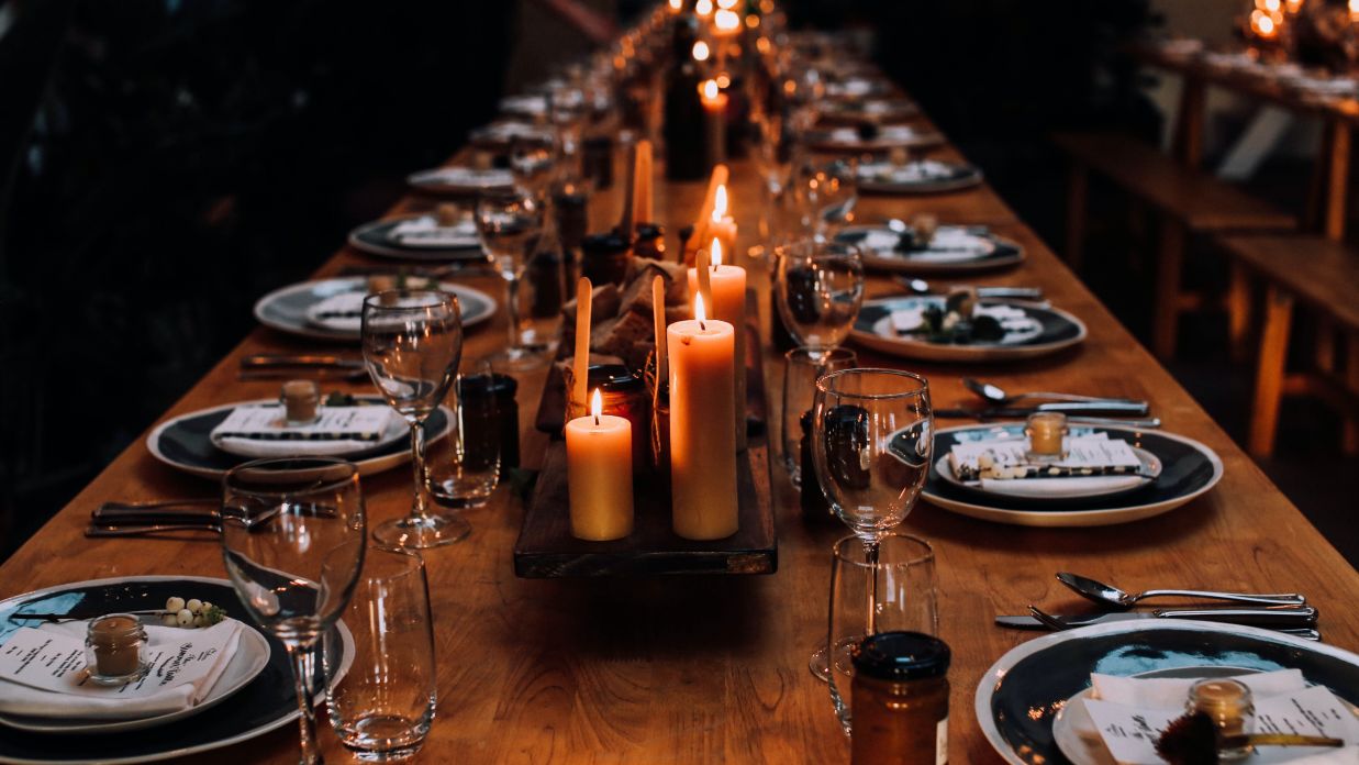 a wedding banquet table with lit candles and plates