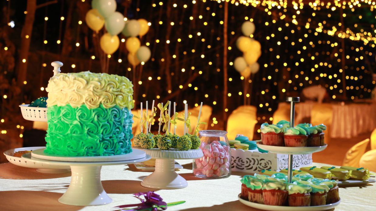 a birthday cake and cupcakes kept on a table