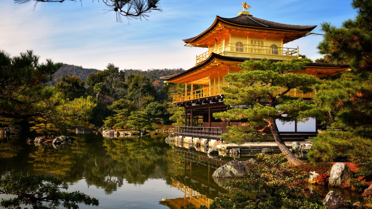 an image of a Buddhist monastery showing the beauty of Buddhist architecture captured during the day amidst a lake surrounded by green trees @ Lamrin Norwood Green, Palampur