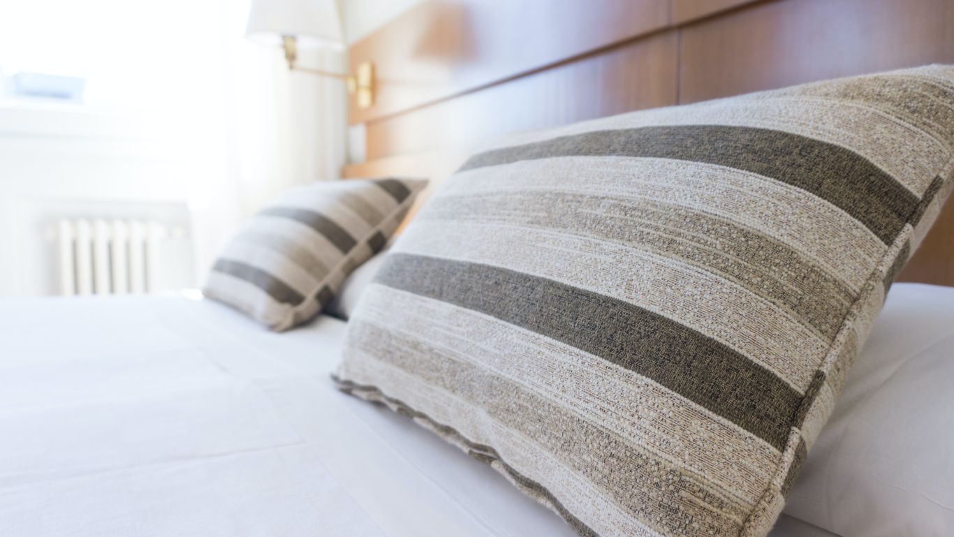 Pillows on top of a bed in a room at a hotel with wooden headboard