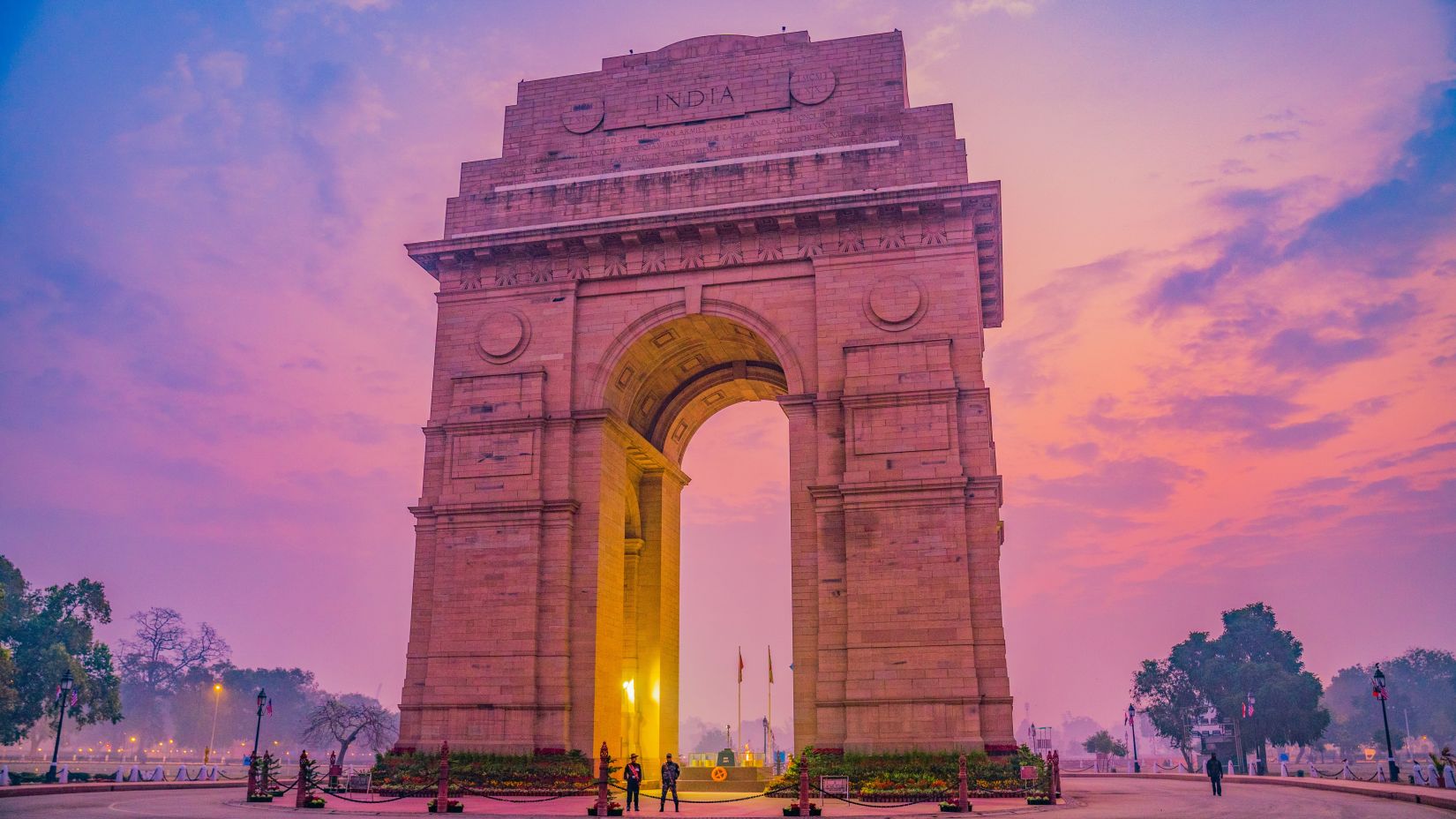 view of the india gate during sunset with a pink hue sky as the backdrop