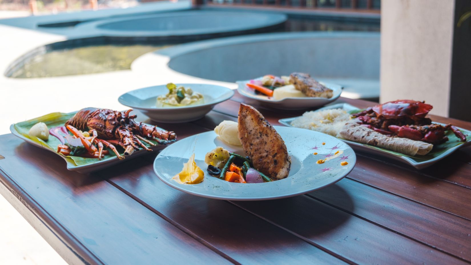 a table with different foods on a plate - Symphony Samudra Beachside Jungle Resort And Spa, Port Blair