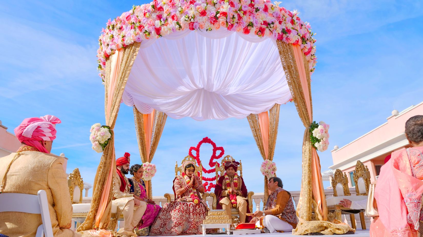 a couple sitting on a chair under red and white floral umbrella