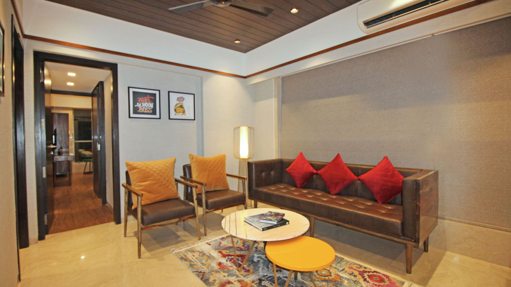 separate living room with brown sofa and yellow and red cushions in khar at theory9