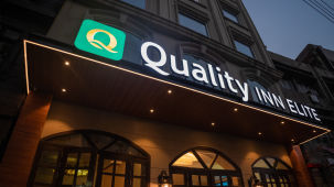 facade view of Quality Inn Elite, Amritsar shot from a lower angle, showcasing the hotel logo and building structure 