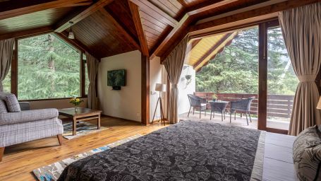 Image of  a room with bed large glass windows and wooden ceiling  at Bedzzz Xclusiv Baikunth, Manali