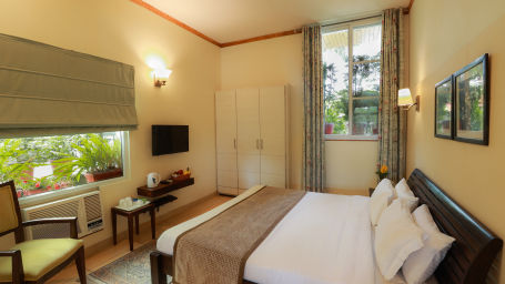 Full angle view of deluxe room with a large window facing the landscape along with room amenities like a television, a wardrobe, etc. - Lamrin Norwood Green, Palampur