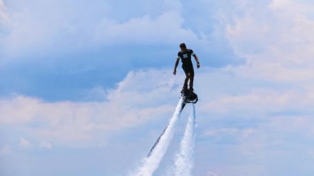 person enjoying fly-boarding under the blue sky