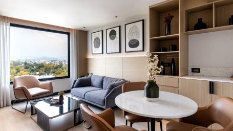 A room featuring a chair, a table with a flower vase on it, a sofa, and a large window offering a great view at Parallel Hotel Udaipur