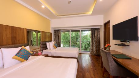 A room featuring twin beds, a TV, expansive windows and a sofa chair - Renest Dunsvirk Court Mussoorie