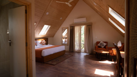 a double bed with windows above the roof and red bed runner on it inside one of the rooms - Samsara Luxury Cottages & Spa