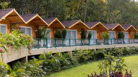 Row of cottages in full view with trees in the background - Stone Wood Jungle Resort, Dandeli