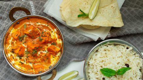 top view of paneer butter masala, papads and rice dish