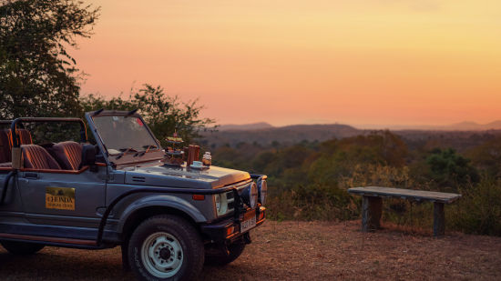 a safari jeep parked next to a bench of a view point with different hues in the sky after the sunset - Chunda Shikar Oudi, Udaipur