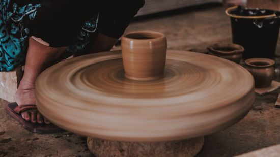 a person making clay glass out of clay with the spinning wheel at the bottom